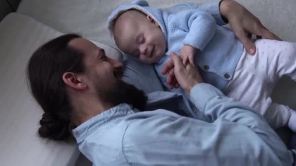 Cinematic Shot Bearded Long-haired Young Neo Father Smiling With Newborn Baby In Nursery At Home. Dad Laying With Infant Child. Children, Parenthood, Childhood, Life, Love, Fatherhood, Family Concept — 图库视频影像