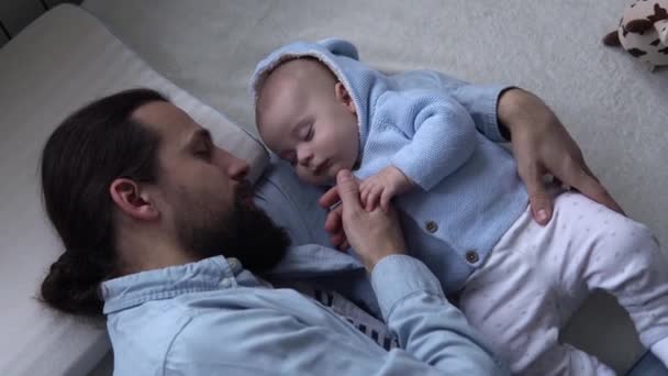Cinematic Shot Bearded Long-haired Young Neo Father Sleeping With Newborn Baby In Nursery At Home. Dad Laying With Infant Child. Children, Parenthood, Childhood, Life, Love, Fatherhood, Family Concept — Vídeo de Stock