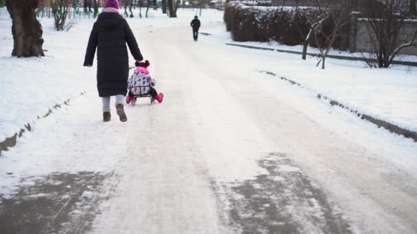 Cute Little Funny White Preschool Girl And Young Mom With Sled Ride Down Slide On Snow In Winter. Children Are Sledding. Baby Walking On Snowy Road Or Path. Childhood, Transportation, Vacation Concept — Vídeo de Stock