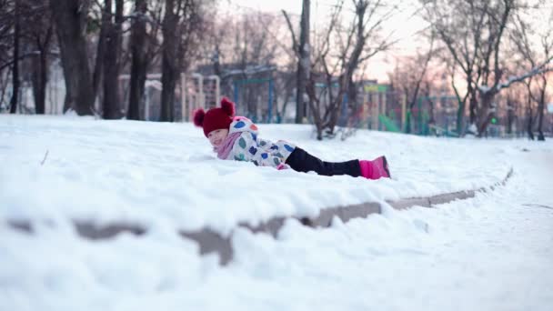 Happy Little divertente bianco prescolare ragazza in giacca colorata con slitta caduta sulla neve in inverno. Bambini carini sono slittino. Bambino che cammina sulla strada innevata o sul sentiero. Infanzia, Trasporti, Concetto di vacanza — Video Stock