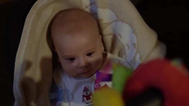 Enfance, maternité, famille, confort. Petit garçon nouveau-né en pyjama de costume blanc éveillé regarde tout autour de sourires joue avec hochets reconnaît largement maman dans la chambre à la maison atmosphère — Video