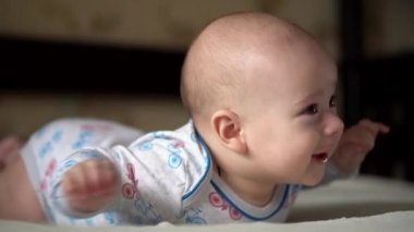 Yenidoğan Aktif Bebek Sevimli Gülümseyen Dişsiz Yüz Portresi Mide Gelişen Boyun Kontrolü Üzerine İlk Günler. 5 aylık çocuk beyaz yatakta kameraya bakıyor. Bebek, Doğum, Ebeveynlik, Başlangıç Konsepti