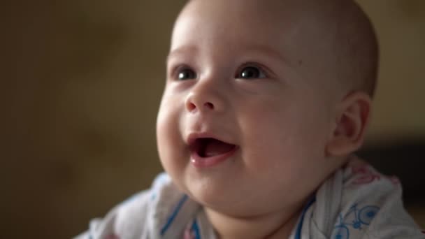 갓 태어난 능동 아기 Cute Smiling Teethless Face Portrait Early Days On Stomach Developing Neck Control. 5 개월된 아이가 흰색 침대에서 카메라를 보고 있습니다. 아기, 출산, 부모로서의 역할, 개념의 시작 — 비디오