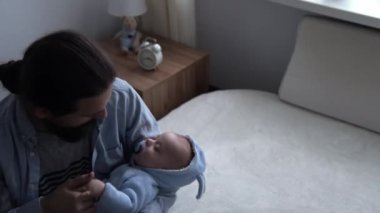Sinematik Çekim Sakallı Uzun Saçlı Genç Neo Baba Evde Yeni Doğan Bebeğin Elini Tutuyor ve Öpüyor. Baba kucağında bebeği tutuyor. Çocuklar, Ebeveynlik, Çocukluk, Hayat, Aşk, Babalık, Aile Kavramı