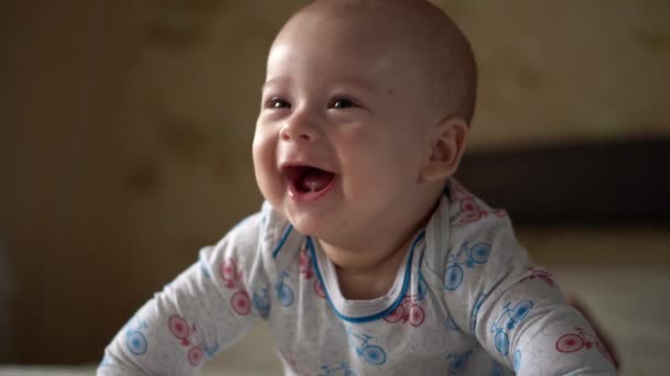 갓 태어난 능동 아기 Cute Smiling Teethless Face Portrait Early Days On Stomach Developing Neck Control. 5 개월된 아이가 흰색 침대에서 카메라를 보고 있습니다. 아기, 출산, 부모로서의 역할, 개념의 시작 — 비디오