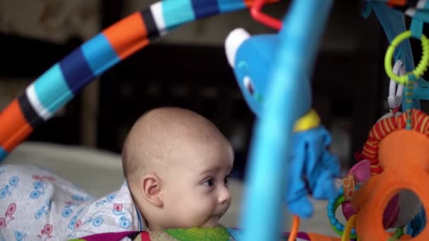 Neonato attivo carino sorridente senza denti Ritratto facciale Primi giorni sullo stomaco Sviluppo del controllo del collo. 5 mesi bambino in box rode giocattoli guardare fotocamera. Neonato, Parto, Concetto iniziale — Video Stock