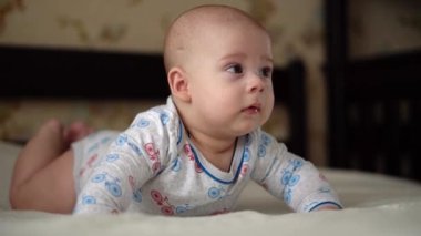 Yenidoğan Aktif Bebek Sevimli Gülümseyen Dişsiz Yüz Portresi Mide Gelişen Boyun Kontrolü Üzerine İlk Günler. 5 aylık çocuk beyaz yatakta kameraya bakıyor. Bebek, Doğum, Ebeveynlik, Başlangıç Konsepti