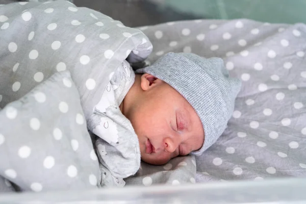 Pasgeboren baby rood schattig gezicht portret vroege dagen slapen in medisch glas bed op grijze achtergrond. Kind aan het begin minuten van het leven op hoed. Zuigelingen, Bevalling, Eerste momenten van Borning, Beginnen Concept — Stockfoto