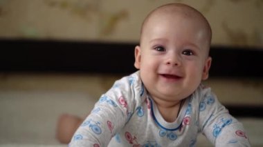 Yenidoğan Aktif Bebek Sevimli Gülümseyen Dişsiz Yüz Portresi Mide Gelişen Boyun Kontrolü Üzerine İlk Günler. 5 aylık çocuk beyaz yatakta kameraya bakıyor. Bebek, Doğum, Ebeveynlik, Başlangıç Konsepti