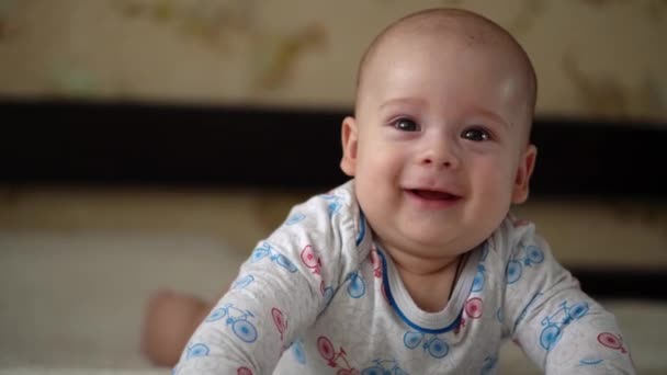 갓 태어난 능동 아기 Cute Smiling Teethless Face Portrait Early Days On Stomach Developing Neck Control. 5 개월된 아이가 흰색 침대에서 카메라를 보고 있습니다. 아기, 출산, 부모로서의 역할, 개념의 시작 — 비디오