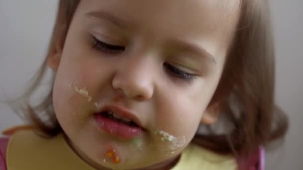 Close-up van vieze gezicht mooie kleine meisje kind eten ontbijt eieren groenten worst alleen thuis. Schattig mogelijkheid gelukkig peuter kind eet aan tafel indoor. Voedsel, voeding gezond leven — Stockvideo