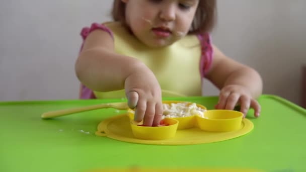 Primer plano de niña encantadora comiendo desayunar huevos verduras salchicha por sí misma en casa. Adorable niño feliz positivo come con la cara sucia en el interior de la mesa. Alimentación, nutrición una vida sana — Vídeos de Stock