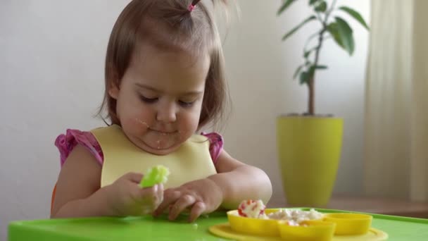 Primer plano de niña encantadora comiendo desayunar huevos verduras salchicha por sí misma en casa. Adorable niño feliz positivo come con la cara sucia en el interior de la mesa. Alimentación, nutrición una vida sana — Vídeos de Stock