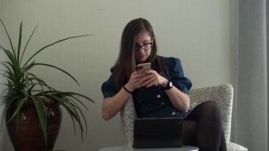Gözlüklü başarılı bir genç kadın telefonda sohbet ediyor. Kullanarak Yazma Araması. Smartphone Browsing Internet 'te çalışan Mutlu Gülümseyen Bayan Buisenes. Eğitim, Teknoloji Konsepti