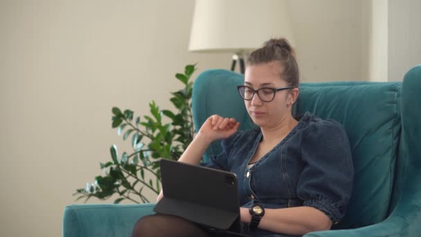 Измученная молодая женщина болтает на ноутбуке в гостиной. Писать с помощью информационных технологий. Нездоровый сонливый перегружен работой на дому, в сфере образования, технологий. — стоковое видео