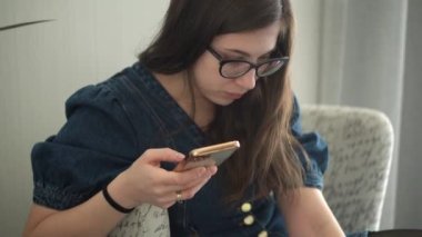 Gözlüklü başarılı bir genç kadın telefonda sohbet ediyor. Kullanarak Yazma Araması. Smartphone Browsing Internet 'te çalışan Mutlu Gülümseyen Bayan Buisenes. Eğitim, Teknoloji Konsepti