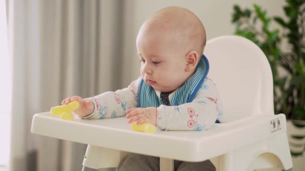 Moeder voeden jong baby in wit voeden tot kinderstoel, eerste supplement plantaardige puree gelukkig lachend kind eten voor de eerste keer, kind met vies gezicht, kleine jongen eten pap voeding — Stockvideo