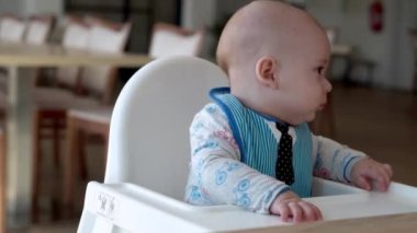 Çocukluk, mutluluk, aile, annelik. Neşeli, mutlu, gülümseyen bebek. Kapan surat. Yeni doğan çocuğun duyguları işte. Önlüklü bir çocuk beslenme koltuğunda oturur, mutfakta kürdan kemirir, bebek sakızı ağrısı...