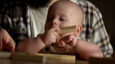 Küçük çocuk, babasıyla küçük jenga oynuyor, anne babası masada, jenga kulesi dağılıyor, aile evde harika vakit geçiriyor güneşli odada oyun oynuyor, mutlu çocukluk, arkadaşlık konsepti.