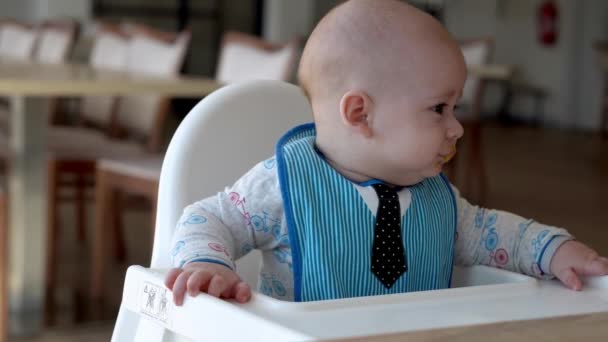 Mama matka karmić młode dziecko w bieli karmienie się wysokim krzesłem, pierwszy suplement przecieru warzywnego Szczęśliwy uśmiechnięty dzieciak jeść po raz pierwszy, dziecko z brudną twarzą, mały chłopiec niemowlę jedzenie żywienia owsianki — Wideo stockowe