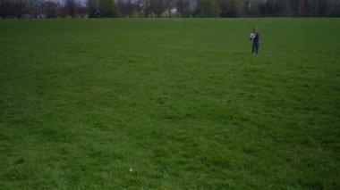 Mutlu çocuk ailesi bahar parkında eğleniyor. Küçük Çocuk Koş. Çocuk Yeşil Çimlerde Siyah Beyaz Klasik Futbol Topu Taşıyor. İnsanlar futbol oynuyor. Çocukluk, Spor, Şampiyonluk Konsepti