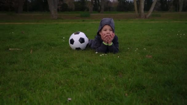 Mutlu çocuk ailesi bahar parkında eğleniyor. Küçük Çocuk Koş. Siyah beyaz klasik futbol topuyla yeşil çimlerin üzerinde yatan çocuk çocuk. İnsanlar futbol oynuyor. Çocukluk, Spor, Şampiyonluk Konsepti — Stok video