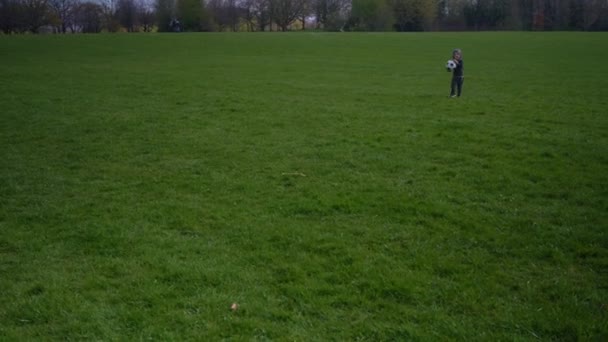 Bonne famille d'enfants qui s'amusent à Spring Park. Little Kid Run. Enfant garçon porte le ballon de football classique blanc noir sur herbe verte. Les gens jouent au football. Enfance, Sport, Championnat Concept — Video