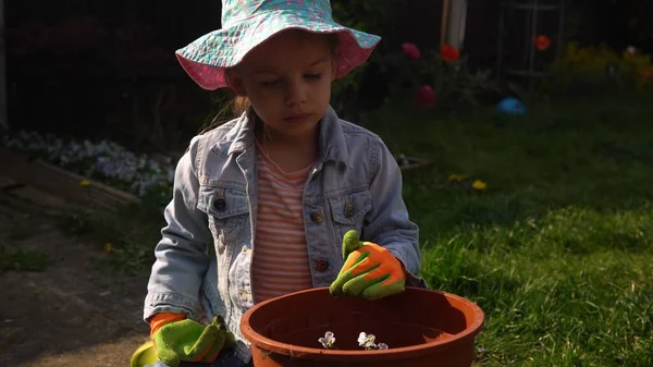 Glad förskola liten flicka unge Dottern bär fungerar handskar humic stövlar plantera blommor i potten i trädgården. Barn som hjälper mamma ut. Familj Natur gardering, miljö Vår Sommar koncept — Stockfoto