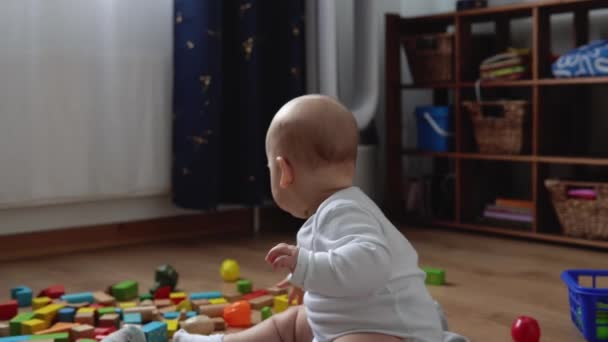 Glad nyfödd baby i lekrummet. Spädbarn barn leka med träleksaker hemma bygga konstruktioner från geometriska figurer. Barn har tillbringat tid under Motor Skills Game. Barndom, föräldrakoncept — Stockvideo