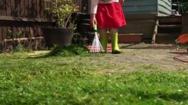 Bahçe bitkileri suluyorum. Yağmurlu botlar giyen çocuk, dışarıdaki güneşli günde yeşil çimen tarlası bitkilerini tırmıklamaya yardım ediyor. Küçük kız, çiçeklerle ilgileniyor. Anneme ev konusunda yardım ediyor. Aile, Çocukluk, Doğa