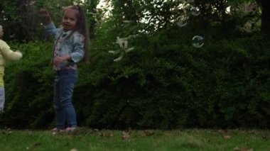 Mutlu bir aile annesi, iki küçük kardeş çocuk sabun köpüğü üflüyor ve yaz tatillerinin tadını çıkarıyorlar. Gülümseyen ebeveynler çocuklar akşam günbatımında birlikte vakit geçiriyorlar.