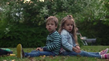Arkadaş özçekimi. Çimlerin üzerinde uzanan heyecanlı çocuklar. Küçük erkek ve kız kardeş kamerada maymunluk yapıyor ve öpüşüyorlar. Aile üyeleri yaz tatilinde parkta birlikte oynarlar.