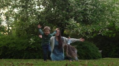 Mutlu aile annesi, koşuşturmaca oynayan üç küçük kardeş anne kucaklaşması yaz tatilinin tadını bahçede ya da parkta çıkarıyor. Gülümseyen ebeveynler çocuklar akşam günbatımında birlikte vakit geçiriyorlar.