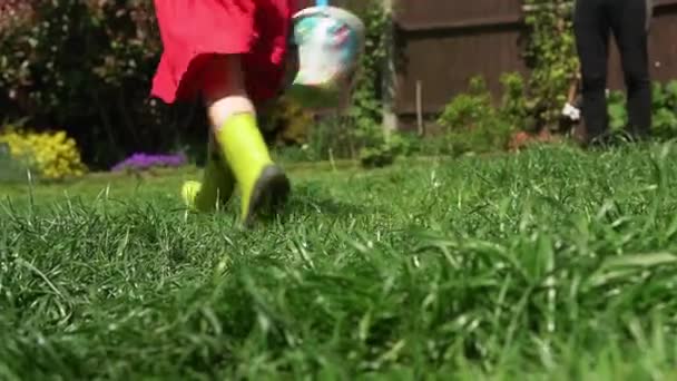 Zavlažování zahradních rostlin. Dítě nosit deštivé boty Běh k fotoaparátu pomoci tráva pozemek rostliny v slunečném dni Venku. Dcera se stará o květiny Pomáhá matce s domem. Rodina, dětství — Stock video