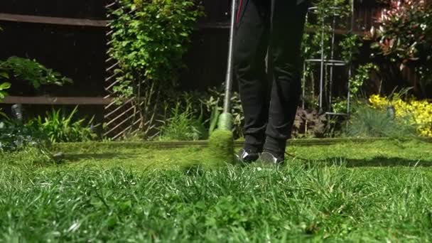 Lawn mower cutting grass. Small Green grass cuttings fly out of lawnmower pushed around by landscaper. Slow motion. Gardener Man working with mower machine in Garden Outside Sunny Day.Family, Work — Stock video