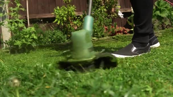 Lawn mower cutting grass. Small Green grass cuttings fly out of lawnmower pushed around by landscaper. Close Up Gardener Man working with mower machine in Garden Outside Sunny Day. Nature Family, Work — Vídeo de Stock