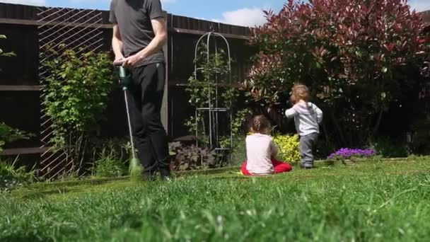 Lawn mower cutting grass. Small Green grass cuttings fly out of lawnmower pushed around by landscaper. Slow motion. Gardener Man working with mower machine in Garden Outside Sunny Day.Family, Work — Stock video