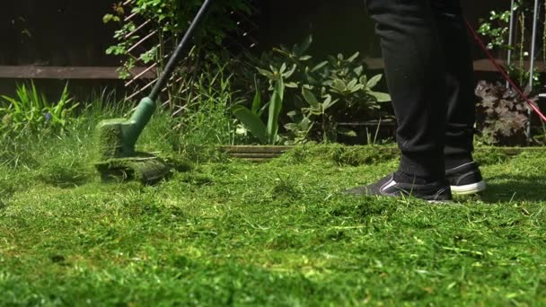 Sekačka seká trávu. Z sekačky na trávu vylétají malé sekačky ze zelené trávy, které obtáčí zahradní papír. Zpomal. Zahradník Muž pracuje se sekačkou v zahradě Venku slunečný den.Rodina, Práce — Stock video