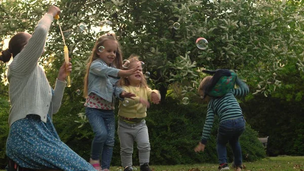 Glückliche Familienmutter, zwei kleine Geschwister, pusten Seifenblasen und genießen die Sommerferien im Garten oder Park. Lächelnde Eltern Kinder verbringen Freizeit zusammen — Stockfoto