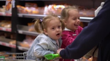 Alışveriş listesi, gıda krizleri, konseptler. Süpermarkette iki kızı olan bir baba. Çocuklar el arabasında oturuyor. Çocuklarla babalar taze sebze ve meyve alır. Sağlıklı beslenme yaşam tarzı. Babalık. 44.