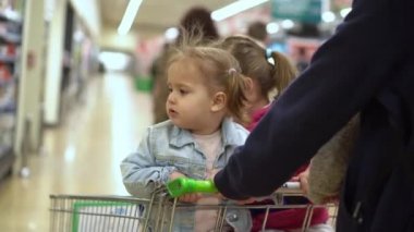 Alışveriş listesi, gıda krizleri, konseptler. Süpermarkette iki kızı olan bir baba. Çocuklar el arabasında oturuyor. Çocuklarla babalar taze sebze ve meyve alır. Sağlıklı beslenme yaşam tarzı. Babalık. 44.