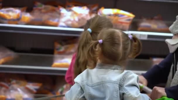 ショッピングリスト食品危機の概念 スーパーで二人の娘と父 子供たちはカートに座っている お父さんと子供の兄弟は新鮮な野菜や果物を購入します 健康的な食生活 44歳 — ストック動画