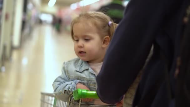 购物清单上的粮食危机概念 父亲和两个女儿在超市 孩子们坐在推车上 孩子们和爸爸一起吃新鲜蔬菜和水果 健康饮食生活方式 — 图库视频影像