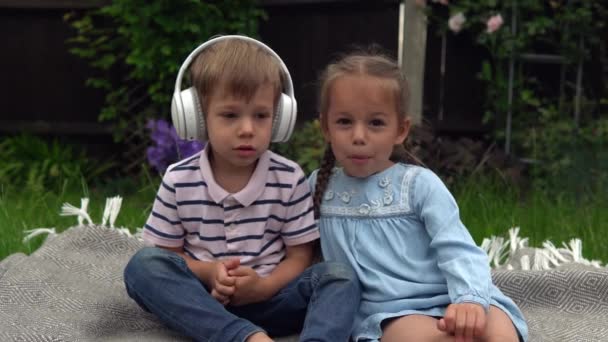 Two Happy Siblings Boy Ans Girl Listening Music Headphones Garden — Stock Video