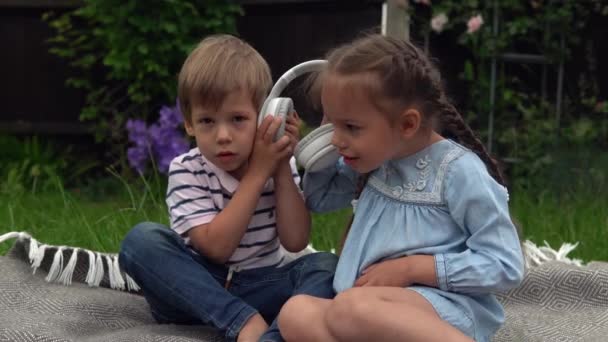 Garden Kulaklıkla Müzik Dinleyen Iki Mutlu Kardeş Çocuklar Teknoloji Erkek — Stok video