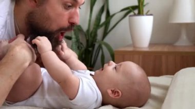 Uzun saçlı otantik sakallı genç baba ve yeni doğmuş bebek yatakta gülümsüyor. Baba, bebek bebekle yatıyor. Çocuklar, Ebeveynlik, Çocukluk, Hayat, Aşk, Babalık, Aile Kavramı