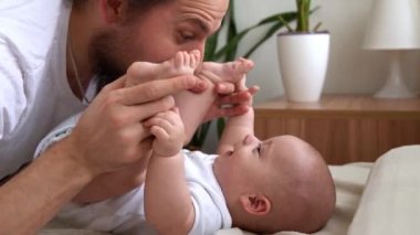 Uzun saçlı otantik sakallı genç baba ve yeni doğmuş bebek yatakta gülümsüyor. Baba, bebek bebekle yatıyor. Çocuklar, Ebeveynlik, Çocukluk, Hayat, Aşk, Babalık, Aile Kavramı