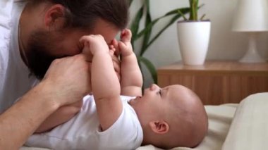 Uzun saçlı otantik sakallı genç baba ve yeni doğmuş bebek yatakta gülümsüyor. Baba, bebek bebekle yatıyor. Çocuklar, Ebeveynlik, Çocukluk, Hayat, Aşk, Babalık, Aile Kavramı