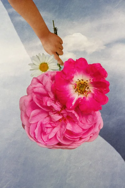 Mano de niña con una flor en el cielo de fondo con nube — Foto de Stock