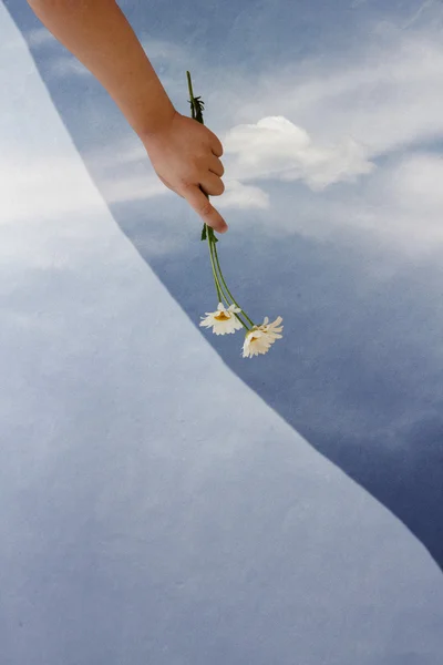 Mano della ragazza con fiori su sfondo cielo con nuvola — Foto Stock